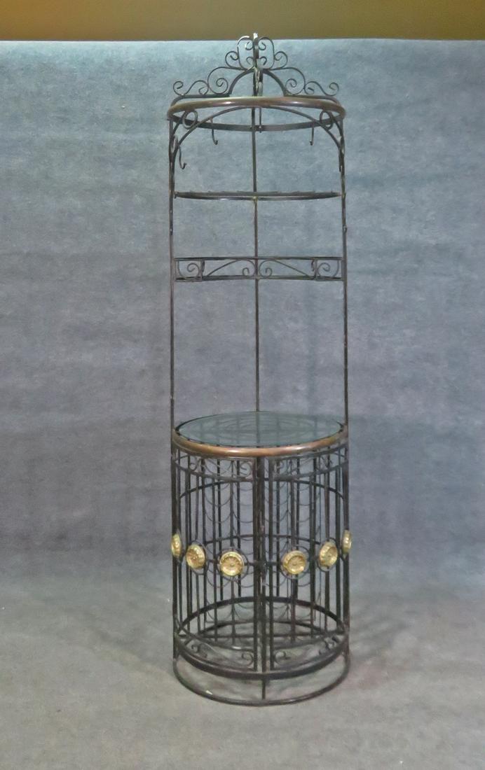 WROUGHT IRON BAKER/WINE RACK: Wrought iron. Brass accents. One glass shelf. Two doors on bottom. 93" h x 26" diameter.