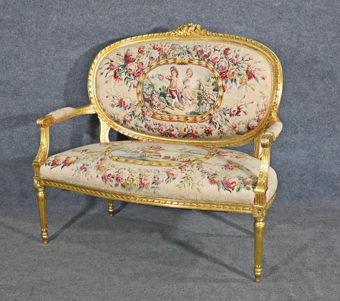 LOUIS XVI AUBUSSON STYLE GILT SETTEE: Carved gilt frame and legs. Aubusson style upholstery. Floral detail. 43 1/4" h 46 1/4" w x 28"d. Seat height 18 1/2".