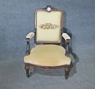 RENAISSANCE REVIVAL CARVED ARM CHAIR MANNER ALEXANDER ROUX: Embroidered back. Front legs on casters. Carved. Upholstered back, seat and arms. Porcelain plaque in bronze frame accented. 41 3/4" h x 26 1/2" w x 26" d. Seat height 17 1/4".