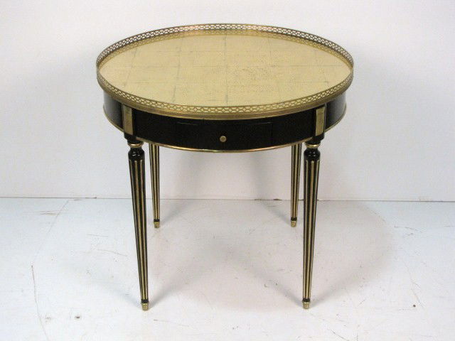 JANSEN LOUIS XVI EBONIZED GILT GLASS ROUND TABLE: Ebonized and gilt. Gold gilt glass top. Bronze mounts and gallery. 28"h. x 29 1/2" diameter.