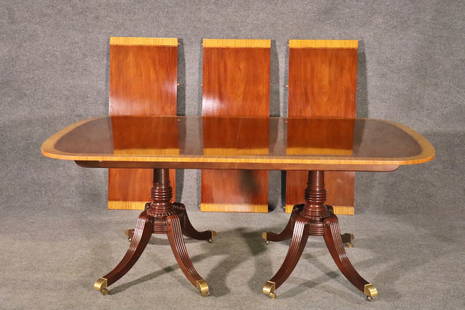 BAKER DINING TABLE: Mahogany. Banded. On casters. Double pedestal base. 28 5/8" h x 73" w x 46 1/8" d. 3 - 18" leaves.