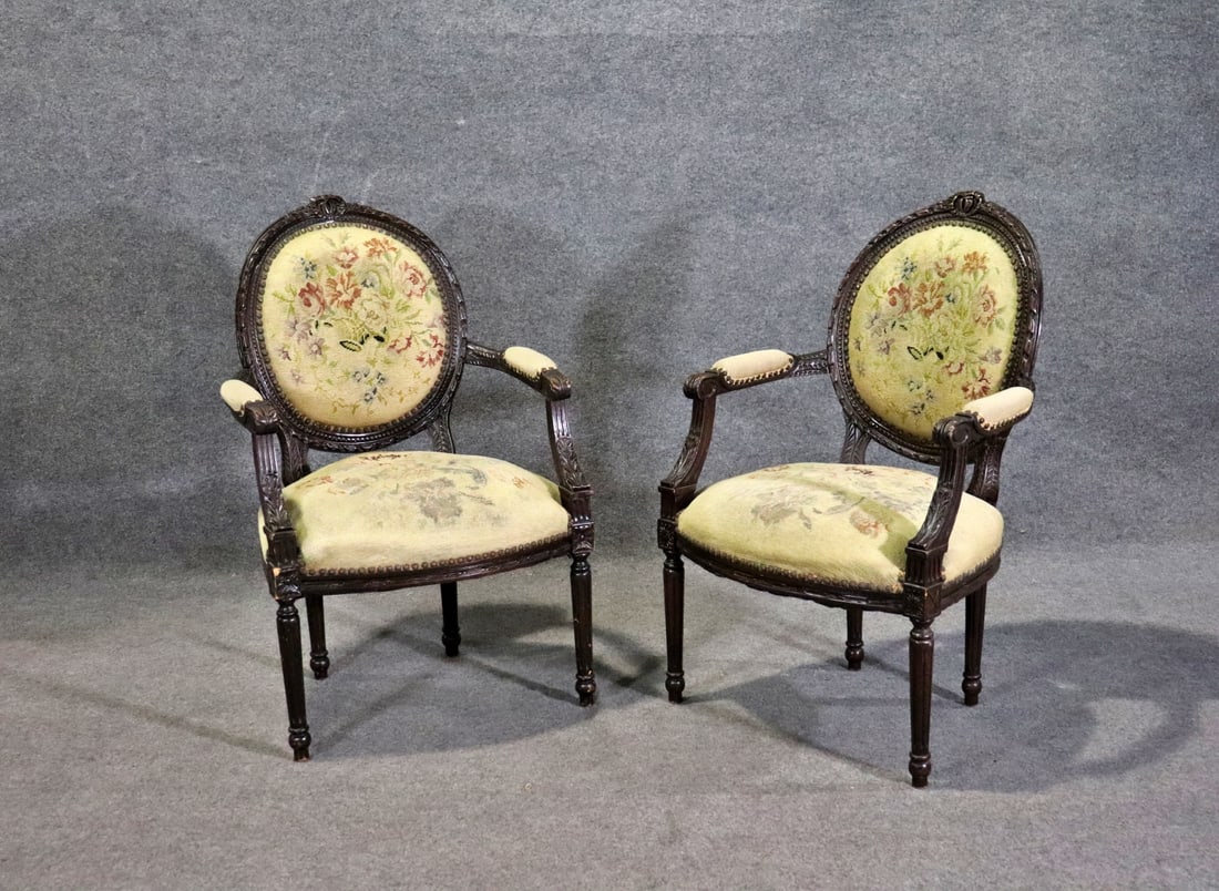 PAIR LOUIS XVI STYLE NEEDLEPOINT ARM CHAIRS: Carved wood frames. Needlepoint upholstery. Nail head trim. 39" h x 25 1/2" w x 15 1/2" d. Seat height 17 1/2".