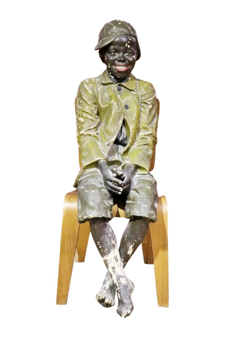 RARE STATUE OF A YOUNG AFRICAN AMERICAN: Plaster. Does not include chair. 43" h x 15 1/2" w x 29 1/2" d.