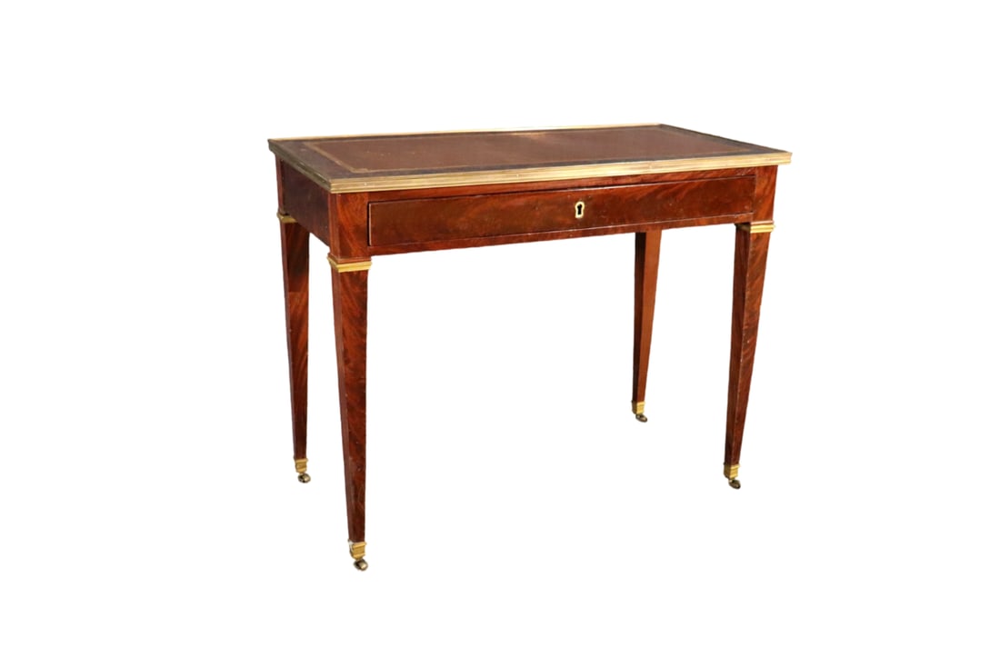 LOUIS XVI LEATHER TOP WRITING DESK: Wood. Leather top. Brass accents and foot caps. On casters. 1 dovetailed drawer. 30 3/8" h x 37 7/8" w x 19" d.