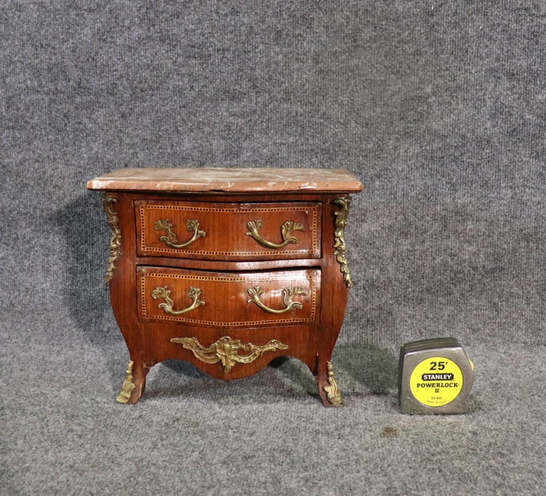 MINATURE INLAID MARBLE TOP COMMODE: Marble top. Brass accents and hardware. 2 dovetailed drawers. Inlaid.10 1/2" h x 11 7/8" w x 7 7/8" d.