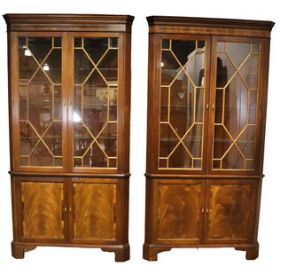 PAIR STICKLEY CORNER CABINETS: Mixed woods. Banded. 2 glass doors on top containing 3 glass shelves. 2 doors on bottom containing 1 shelf. Metal hardware. Lighted. 84" h x 43 3/4" w x 19 3/4" d.