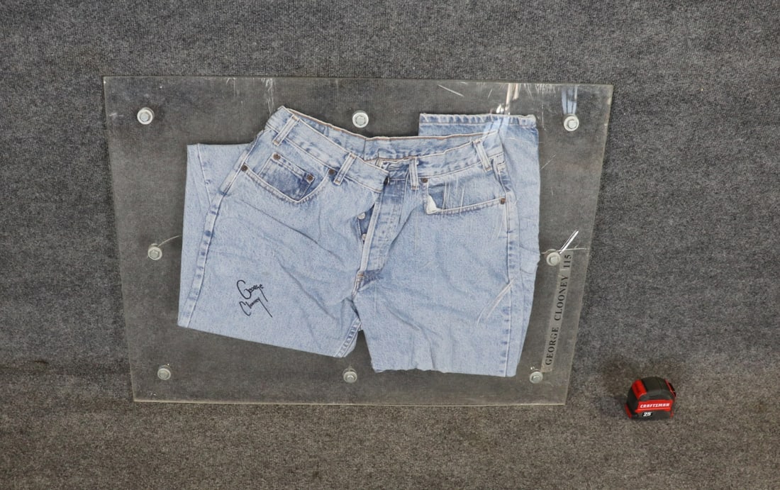 SIGNED & FRAMED GEORGE CLOONEY JEANS: Signed George Clooney. Lucite frame. Framed measures 24" h x 32 1/4" w x 2" d.