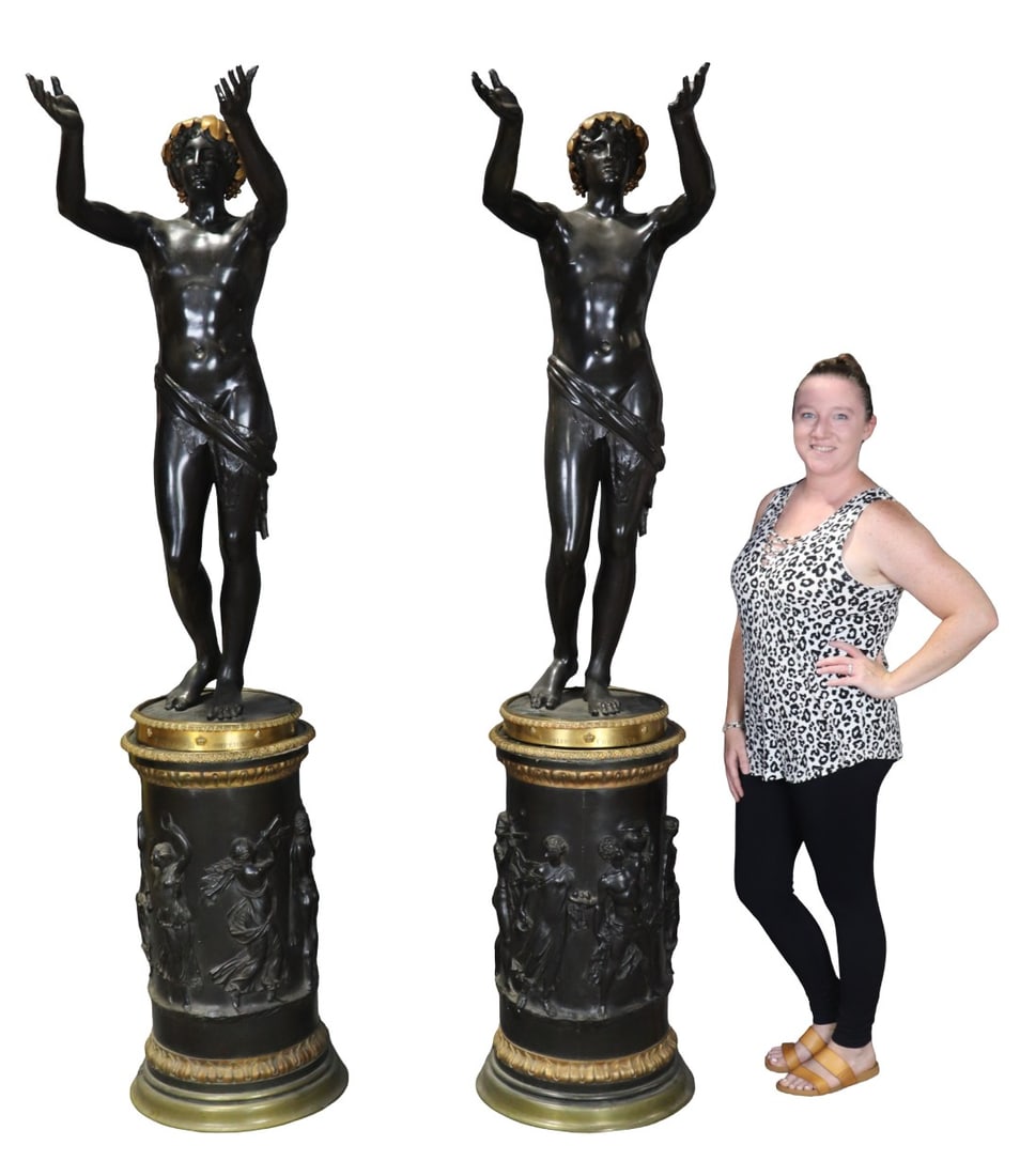 PAIR BRONZE FIGURAL MEN WITH BRONZE MOUNTED PEDESTALS: Patinated and gilt bronze. Figural. Pedestals measure 33" h x 20" diameter. Figures measure 52 5/8" h x 17 3/4" w x 21 1/2" d.