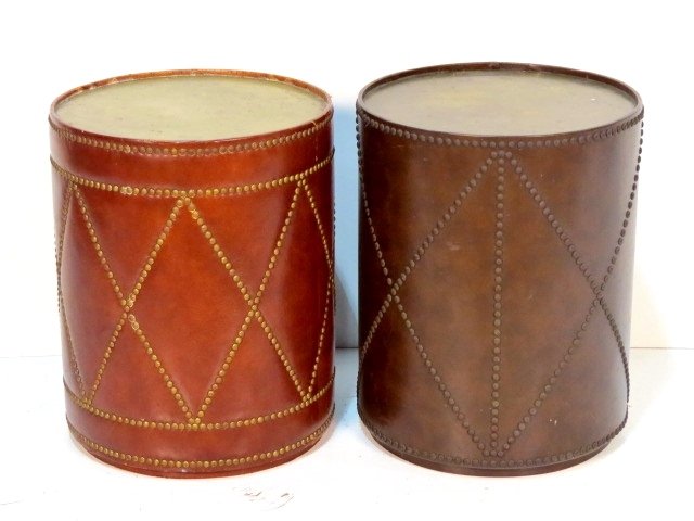 COMPANION SET OF STUDDED LEATHER DRUM TABLES: Brass tops. One in good condition. One in fair condition with wear and small damages. Each approximately 23"h. x 18" diameter.