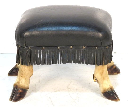 FRINGED BLACK LEATHER DEER HOOF FOOTSTOOL: Four deer feet with leather upholstery. 14"h. x 19"w. x 15 1/4"d.