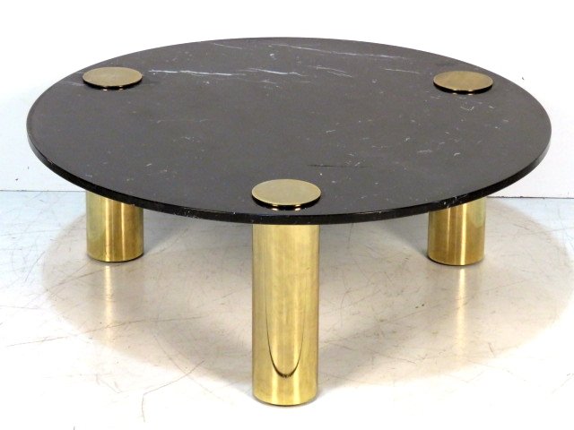 MILO BAUGHMAN STYLE BRASS & MARBLE COCKTAIL TABLE: Round black marble with cylindrical brass legs. 16 1/2"h. x 42"diam.