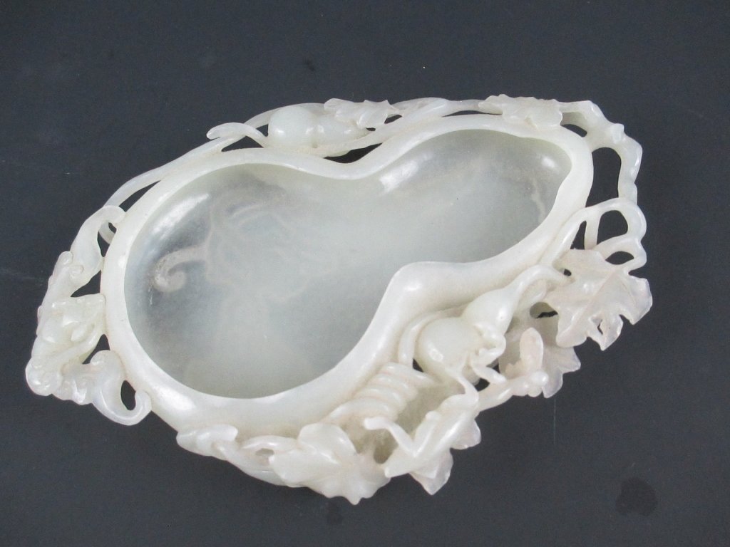An Antique Chinese Carved White Jade Brush Washer: Possibly 19th century, the thinly carved jade of even icy-white color, of double-gourd form, the shallow interior below the pierce-carved exterior having gourds, leaves and vines in high relief, a man