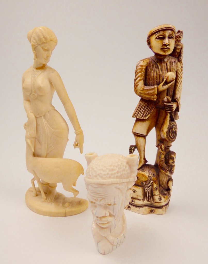 Three Carved Ivory Figures: The group comprising a diminutive African bust of a man, an Indian figure depicting a lady with a deer, and a Southeast Asian figure depicting a man with a monkey.Size: 6" H (largest) Provenance: Prop