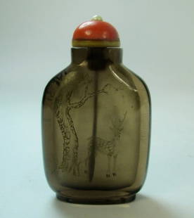 An Antique Chinese Carved Tea Crystal Snuff Bottle: An antique Chinese tea crystal snuff bottle, of flawless tea colored crystal, one side incised with gold depicting a deer underneath a pine tree. SIZE: 2.75" H