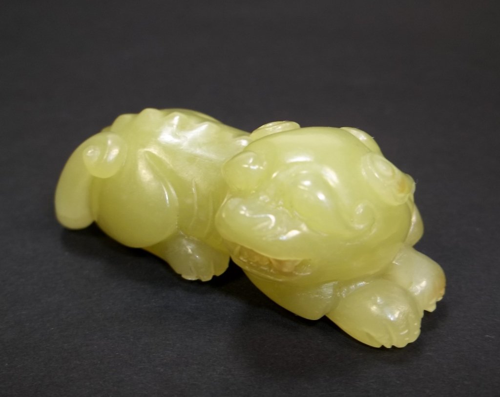 A Chinese Carved Yellow Jade Lion: A Chinese yellow jade carving depicting a reclining fu lion, of yellow greenish color, 2.125" L