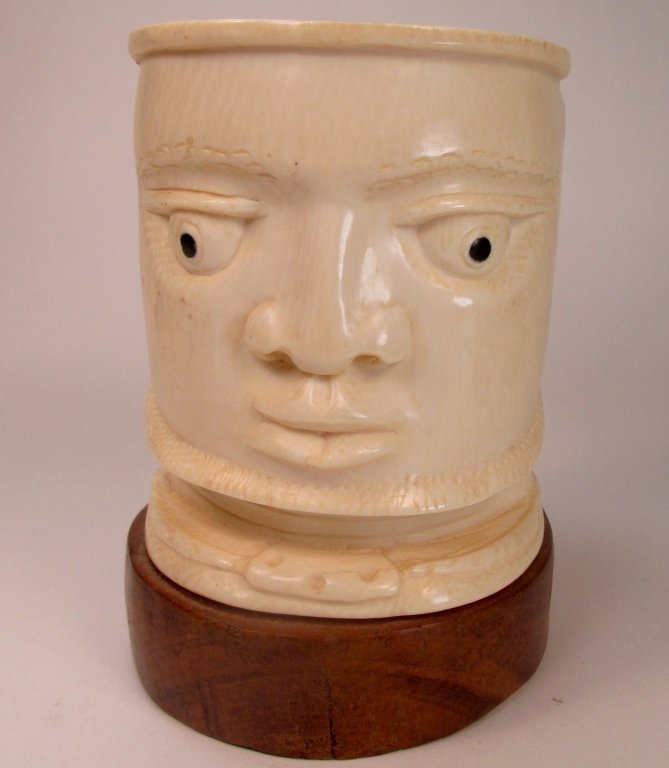 An African Carved Ivory Figural Vase: An African carved ivory figural vase, depicting the bust of a man, raised on the affixed wooden base. Size: 4 3/4" dia. x 4 3/4" H (exclusive ofbase) Provenance: Property from a Private Collection, Su