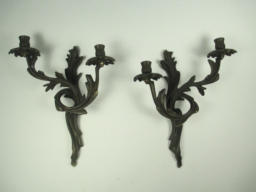 A Pair of Italian Patinated Metal Louis XVI Style: The patinated metal wall sconces each of scrolling foliate form, having two receptacles, and marked to reverse Made in Italy. Size: 11" L x 13 1/4" H