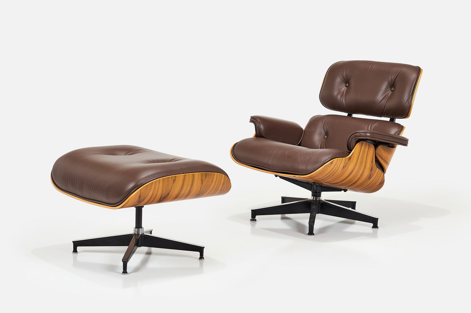 Charles + Ray Eames, Lounge Chair + Ottoman (2): CHARLES + RAY EAMESLounge chair and ottoman, model nos. 670 and 671, 2010Walnut, leather, aluminum. Manufactured by Herman Miller, USA.Underside of each with manufacturer's labels. Chair: 31.5" H x 33