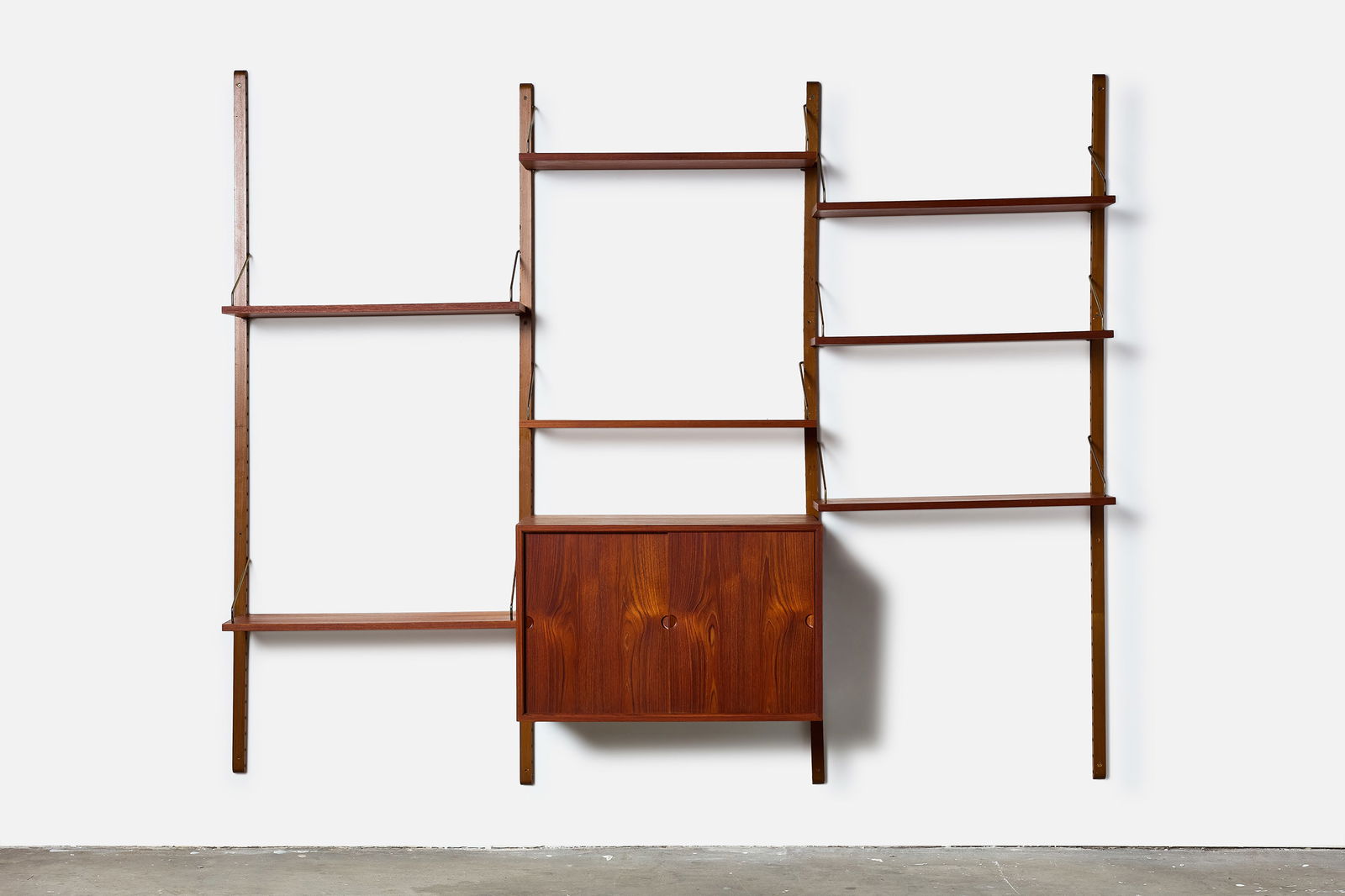 Poul Cadovious, 'Royal' Wall Unit: POUL CADOVIUS 'Royal' wall mounted shelving unit, 1960s Teak, brass. Manufactured by Cado, Denmark. 78" H x 98" W x 16" D