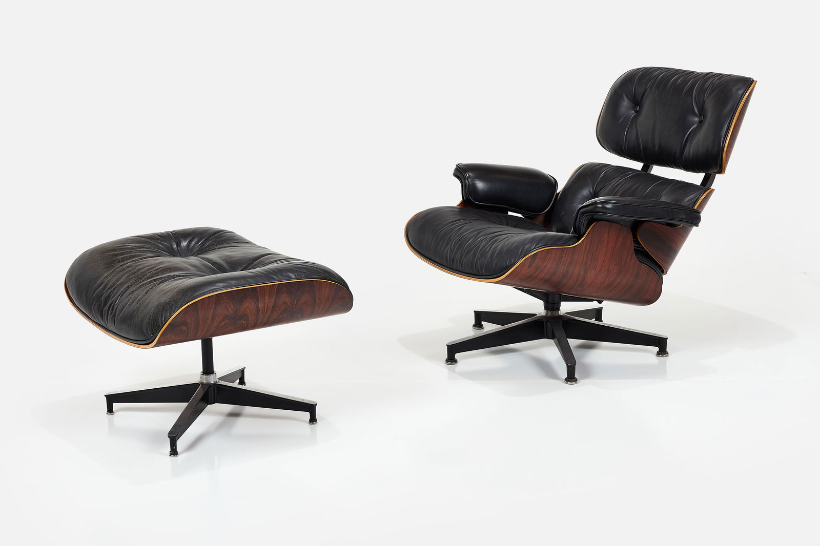 Charles + Ray Eames, Lounge Chair + Ottoman (2): CHARLES + RAY EAMESLounge chair and ottoman, model nos. 670 and 671, ca. 1980Rosewood-veneered plywood, leather, enameled and brushed aluminum. Manufactured by Herman Miller, USA.Underside of each wit