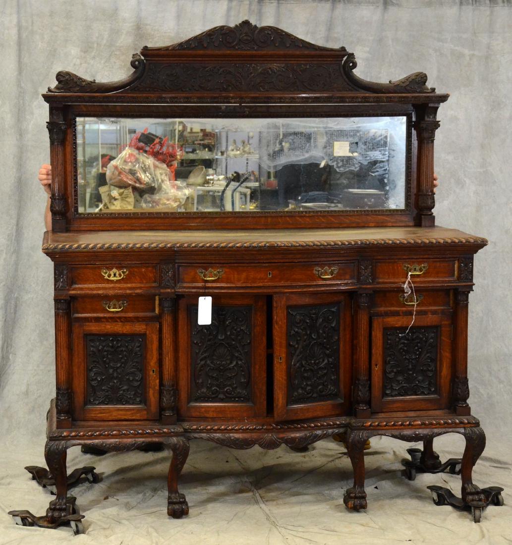 Oak Victorian 2 pc sideboard w/ mirror: Oak Victorian 2 pc sideboard w/ mirror, acanthus carved decoration flanked by dolphins over a beveled glass mirror, 3 drawers over 4 decorated doors, brass hardware, claw feet, 78"h x 67"w x 28"d
