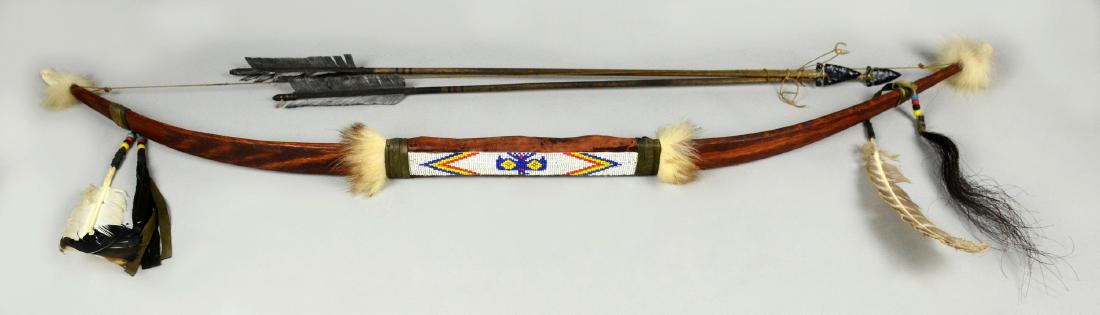 Native American Beaded Bow & Arrows: Native American Bow & Arrows, wooden bow with beaded geometric design, leather wrapped grip, figural eagle carved bone tips, adorned with fur, feathers, beads, and horse hair, along with 2 arrows, 47"