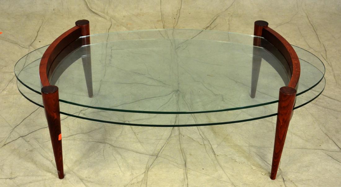 Modern design two tier plate glass coffee table: Modern design two tier plate glass coffee table, bowed mahogany finished ends slatted sides with oval glass inserts, lower shelf fitting into slotted ends, 16-1/4"h x 50-1/2"w