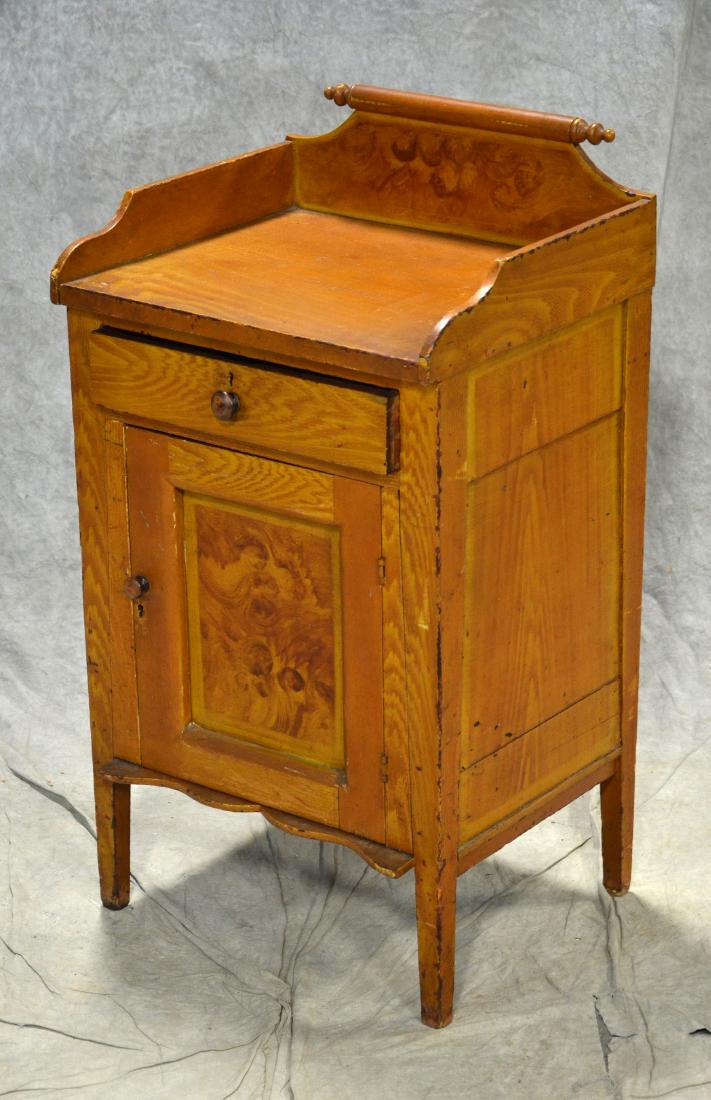 Grain painted closed washstand: Grain painted closed washstand, with one drawer over paneled door, square tapered legs, with scalloped bottle board, dovetailed gallery with rolling pin top, paneled ends, excellent original paint, 19