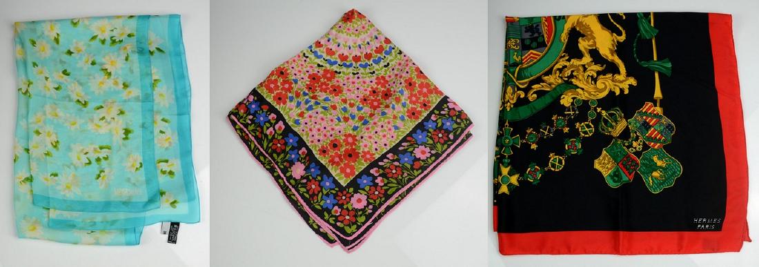 Silk Scarf Grouping: Silk scarf featuring crest with raised lions, tassels, flags and jewels. Black ground with red surround. 33" x 34". Lot also includes floral Schiaparelli scarf and Moschino daisy scarf.