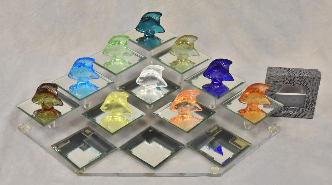 (10) Lalique Poisson Fish Figures: (10) Lalique crystal Poisson fish figurines, different colors, marked "Lalique France", each 1-3/4" h x 2" w, with lucite & mirror display stand, 17-1/4" w, with original boxes
