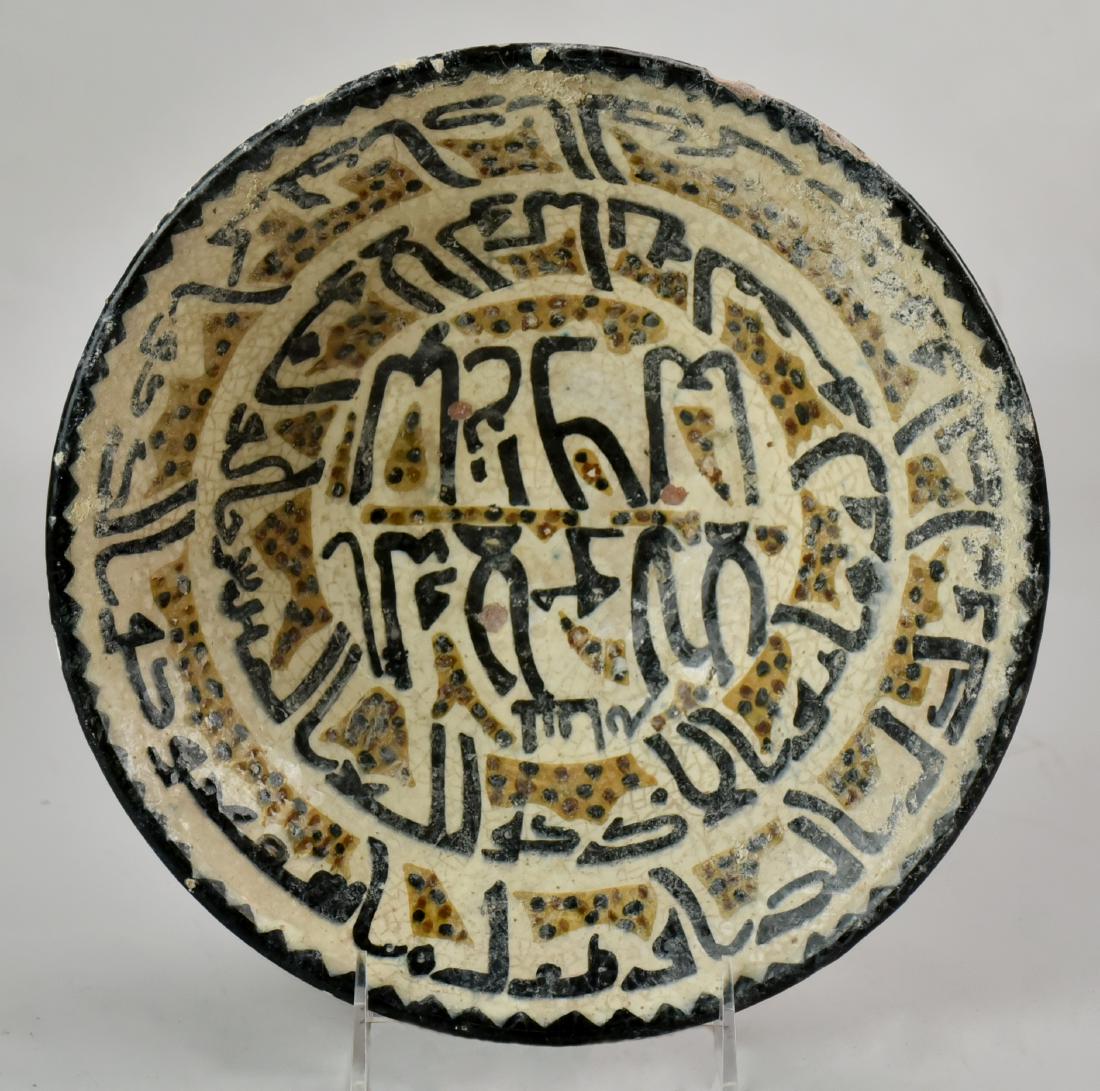Dish With Large Central Medallion: An indigo, burgundy and white under-glazed dish, the flared lip decorated with two wide bands of stylized calligraphy above a large central medallion with two lines of calligraphy, Iran. Size 12" Cir.
