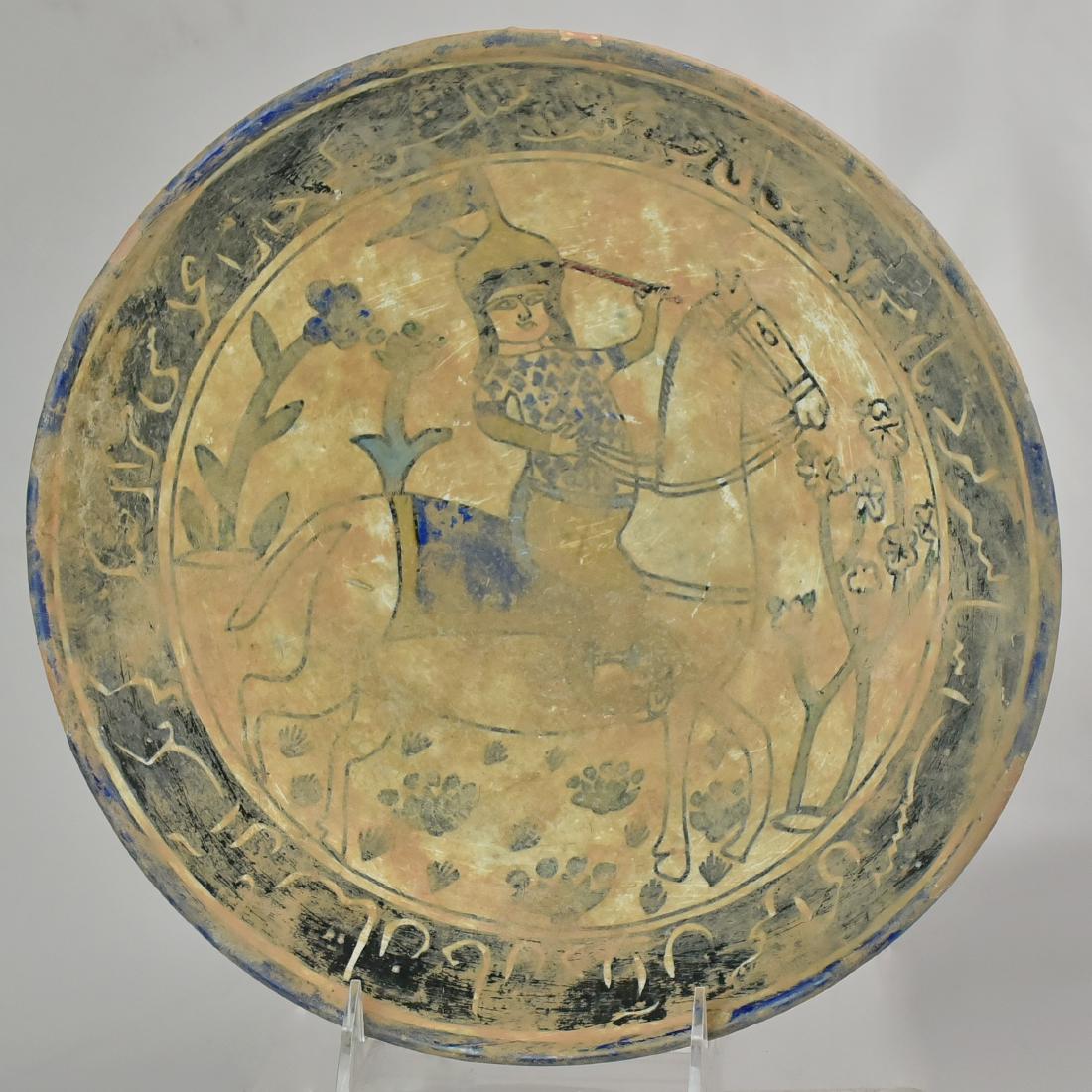 Stoneware Afghan Serving Dish: A blue and white under-glazed stoneware serving dish, decorated with a warrior on his horse amidst flowers, the flattened lip decorated with a wide band of calligraph, Afghanistan. Size 10" Dia.