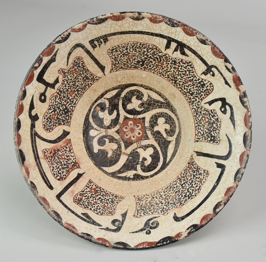 Stoneware Afghan Bowl: A rust, dark blue and white under-glazed stoneware bowl with flared sides, decorated with a floral central medallion followed by a wide band of calligraphy, interspersed with speckled shapes and a sca