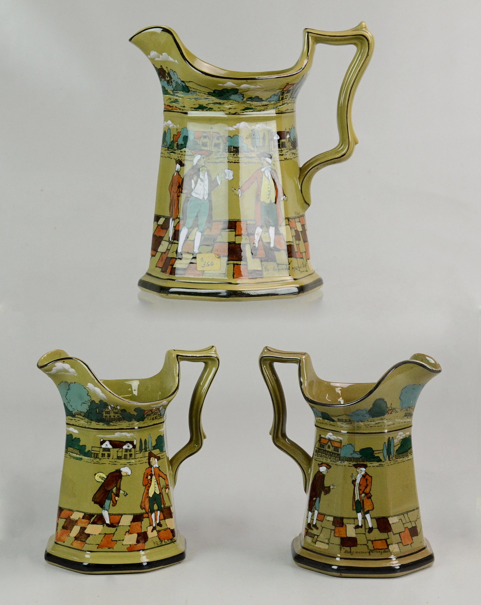 (3) BUFFALO POTTERY DELDARE PITCHERS: (3) BUFFALO POTTERY DELDARE PITCHERS, "To Demand my Annual Rent", 8" h; (2)_ "Their Manner of Telling Stories", 6"h, one with repaired spout