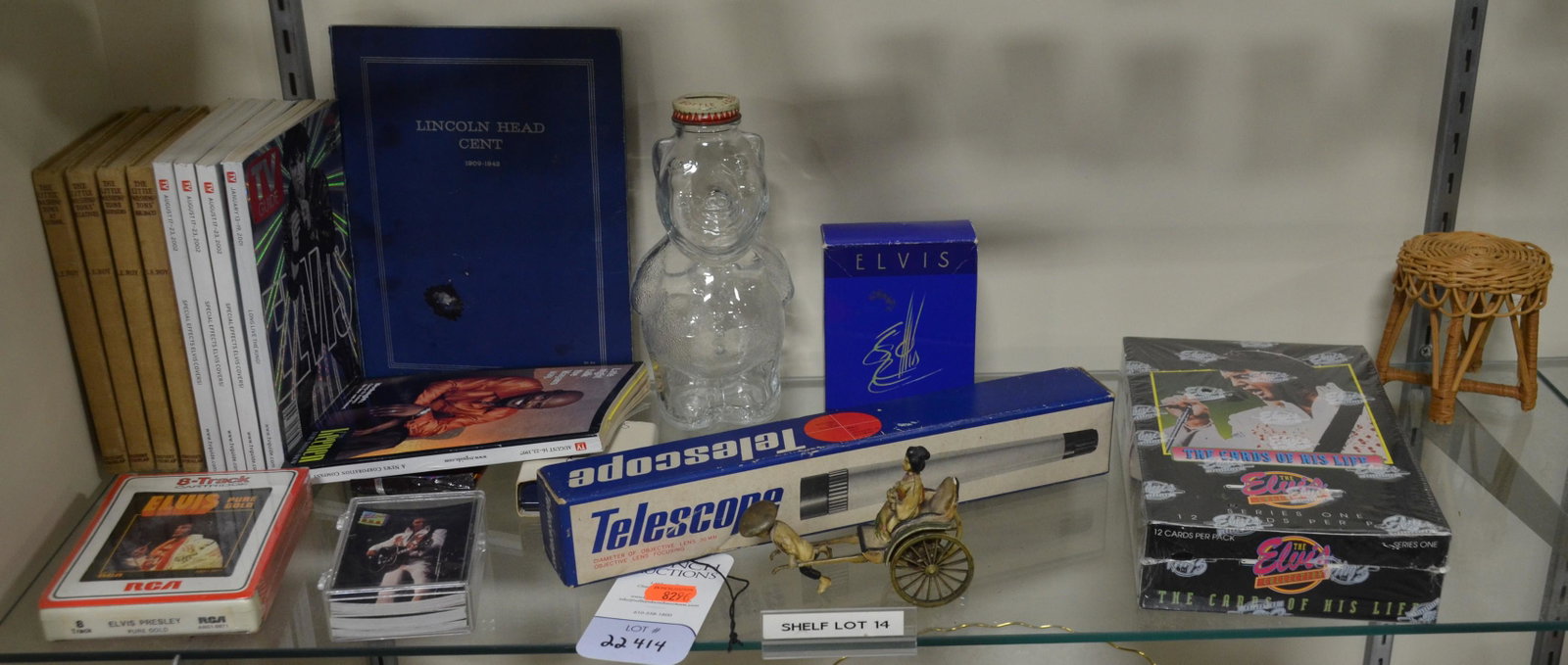 Shelf #14 - Elvis Lot: Shelf #14 - Elvis Items Including Trading Cards of His Life, Elvis Pin, Elvis Aftershave Bottle, (5) Elvis TV Guides, Sealed Elvis 8-Track, (4) The Little Washington's Holidays Books, Snow Crest Bear 