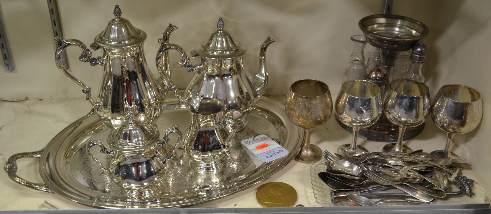Shelf #30 - Silver Plate Items Including Cruet Set: Shelf #30 - Silver Plate Items Including: Cruet Set, International Silver Tray and (4) Piece Tea Set, (4) Goblets, and Silverware Utensils, Bronze Coin