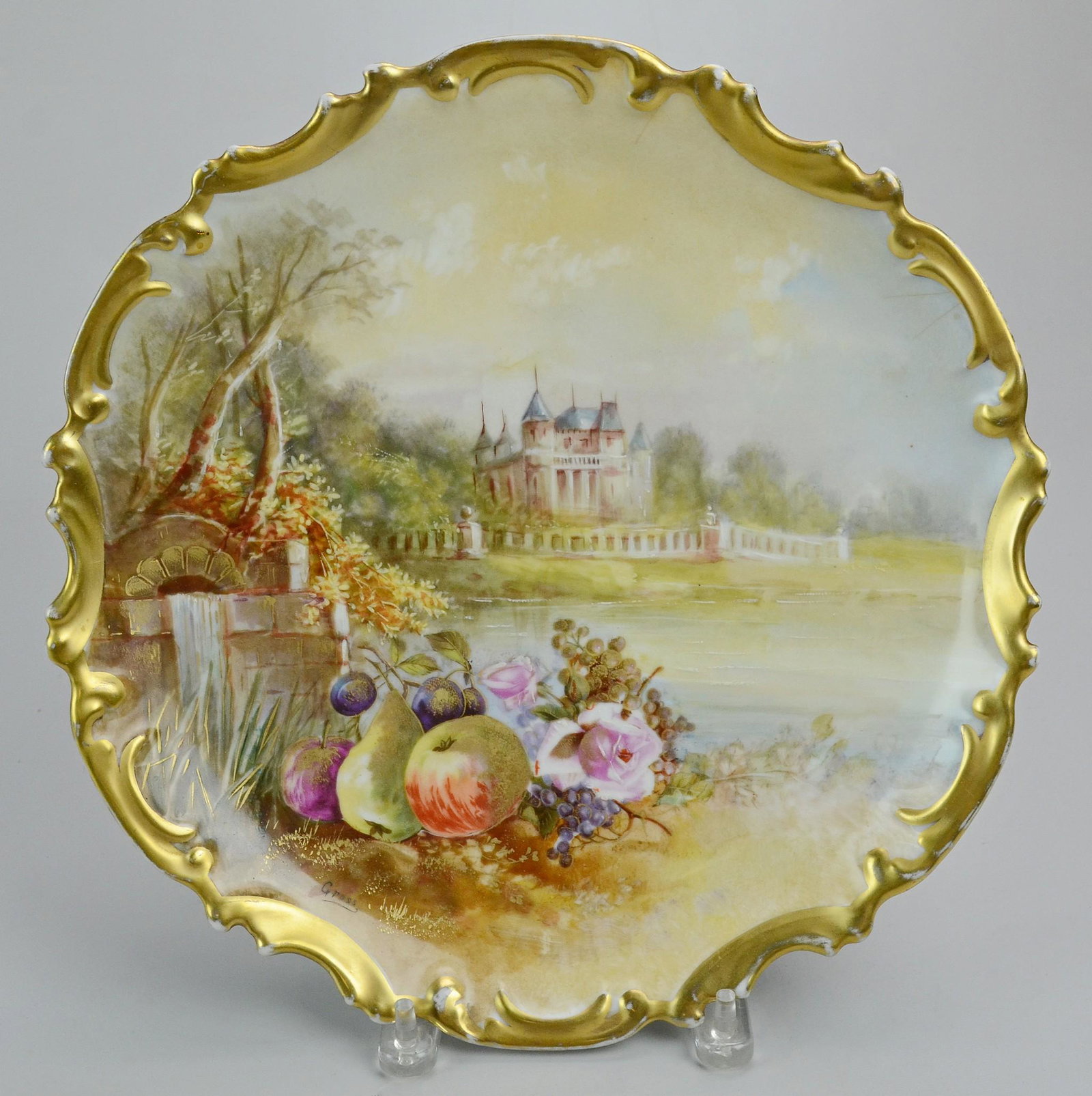 Unmarked Continental Porcelain Charger: Unmarked continental porcelain charger with Rococo gilt border. Depicts handpainted and transfer scene of chateaux, lake landscape, fruit and flowers. Artist signed "Gross", (13" dia)