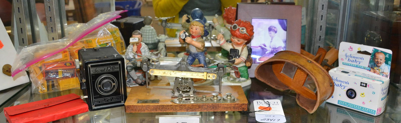Shelf #17 - Cameras, Figurines, Stereopticon: Shelf #17 - Scout 120 Boy Scout camera, photographic exposure calculator 1922, Stereopticon viewer, 2 Goebel figurines, Norman Rockwell figurine, Kodak avoirdupois scale (missing pans & one weight), b