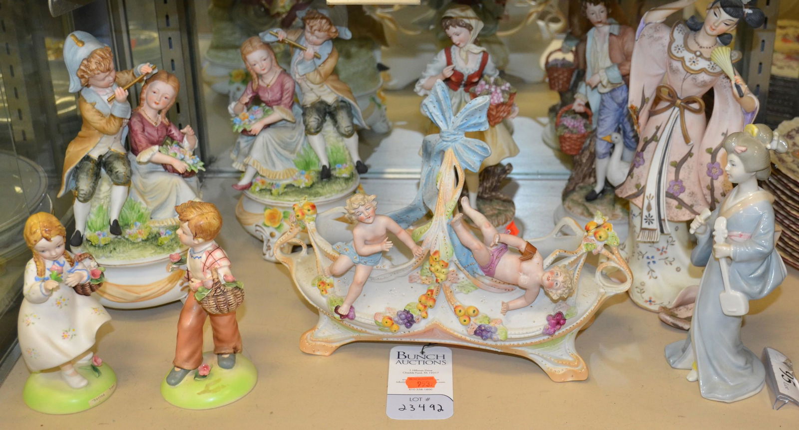 Shelf #95 - Ceramic Figures: Shelf #95 - Ceramic Figures Including: (2) Andrea Sadek Figures of Boy Playing Flute with Girl, (2) Lefton Figures of Man and Woman with Basket and Goose, Capodimonte Basket with Cherubs (Broken Finge