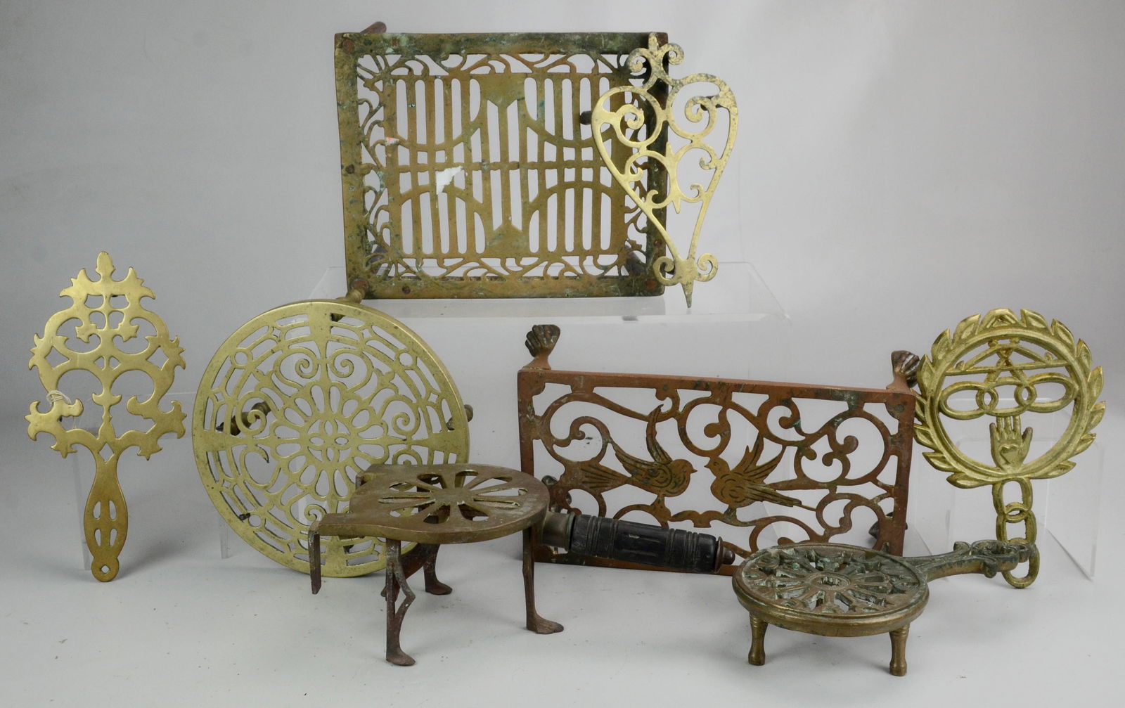 Lot of Brass and Cast Iron Trivets: Lot of Brass and Cast Iron Trivets Including Wilton, a Heart Shape, and One with Bird Decoration and Paw Feet