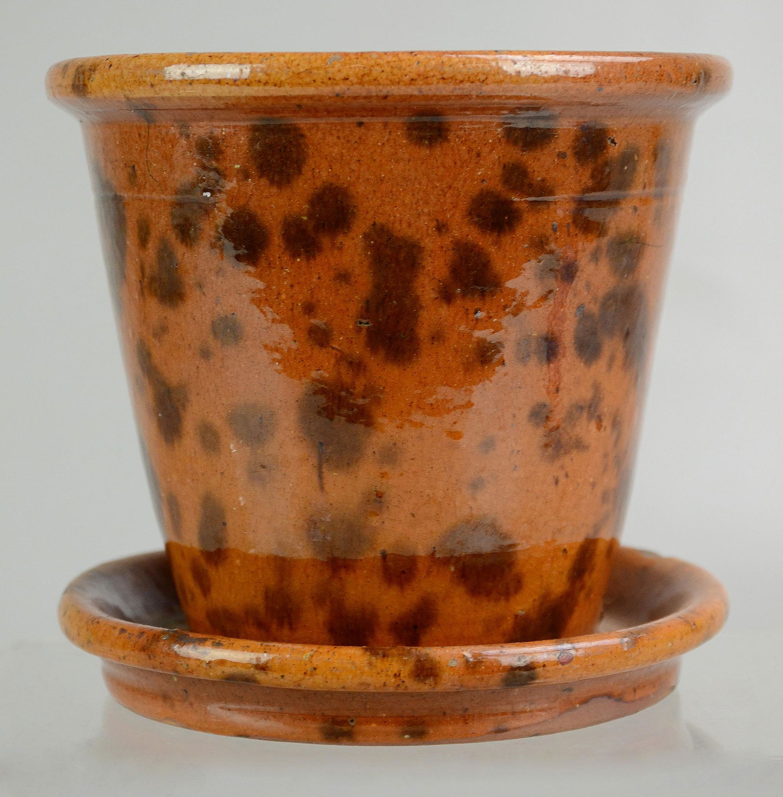 Willoughby Smith, Womelsdorf, PA Redware Flower Pot.: Willoughby Smith, Womelsdorf, PA Redware Flower Pot. Splotched manganese decoration, tapered body and attached saucer base. Stamped "W. Smith Womelsdorf" on base. 5" h, no damage noted
