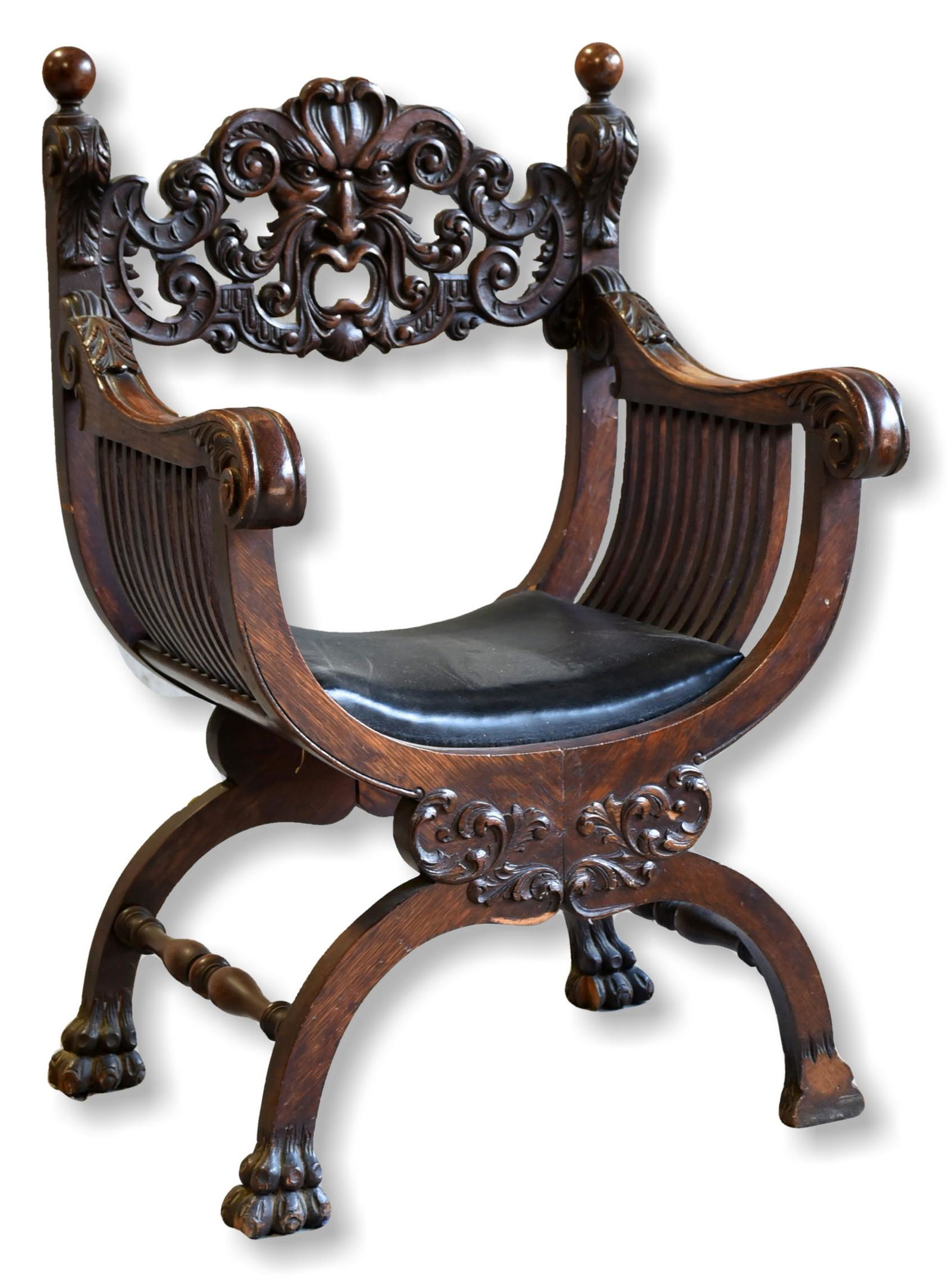 Oak carved Savonarola chair: Oak carved Savonarola chair, pierced back with northwind face, acanthus leaf decoration over scrolled arms, paw feet, black leather seat, 41" h x 22" w x 22" d, back right leg missing piece, back left