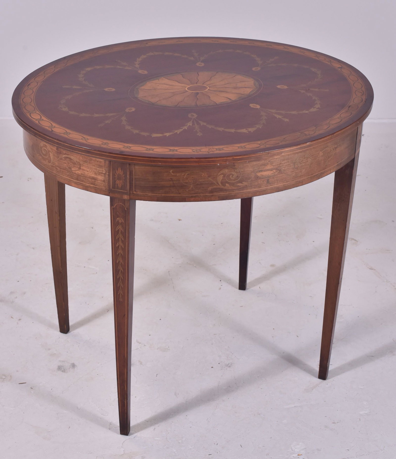 Mahogany Hepplewhite oval inlaid center table: Mahogany Hepplewhite one drawer oval inlaid center table, bellflower and urn decoration, glass top, marked on paper tag Estate of Charlotte L Frelingheyaz, July 25, 1930, 30"h x 34"w x 28-1/2"d