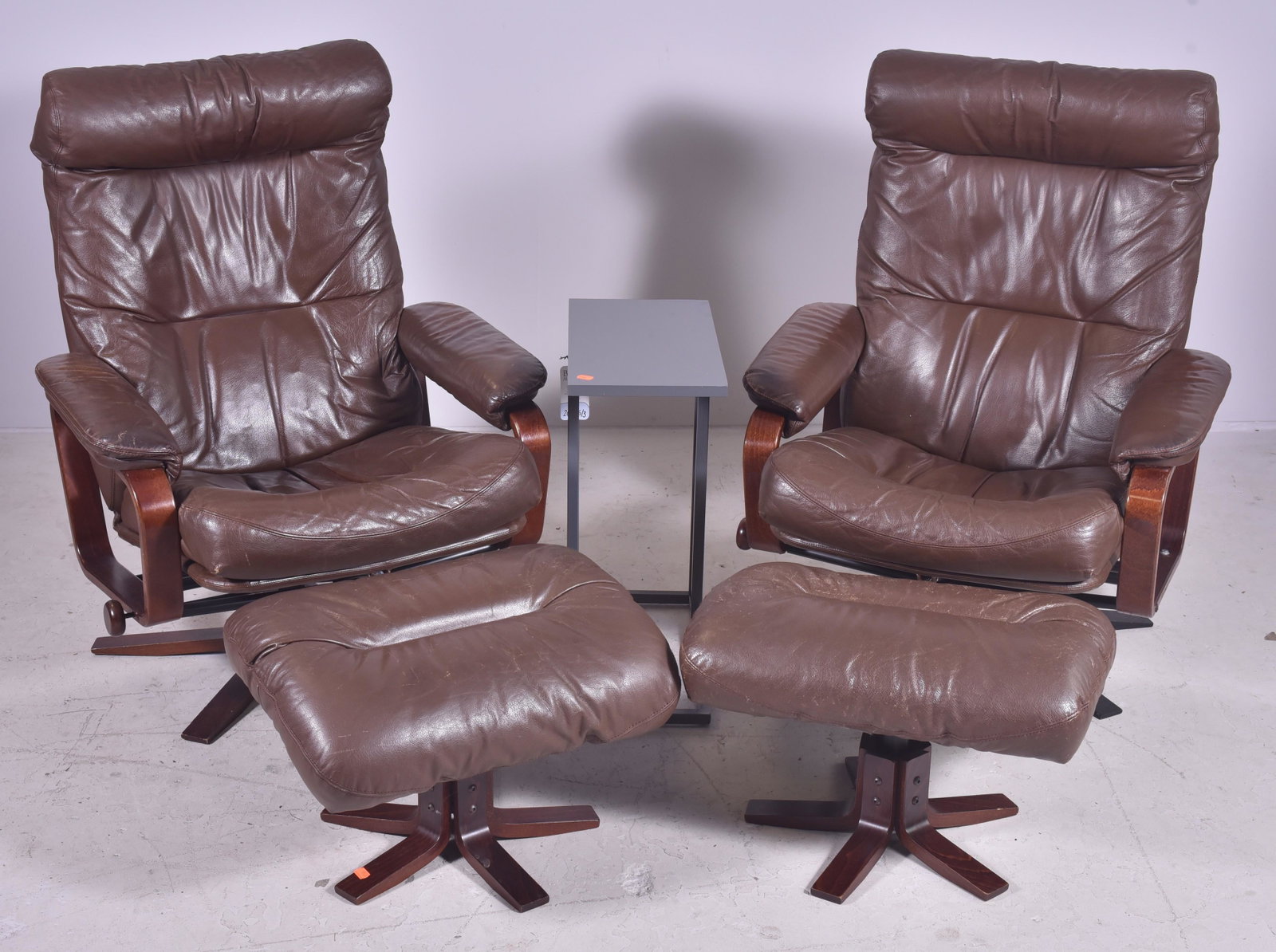 Pr Skippers Mobler leather & rosewood chairs: Pair Skippers Mobler leather & rosewood lounge chairs w/ ottomans, brown leather, sticker label on bottom, 40" h x 31-1/2" w x 25" d, seat height 18" h, one chair with base replaced, leather in used c