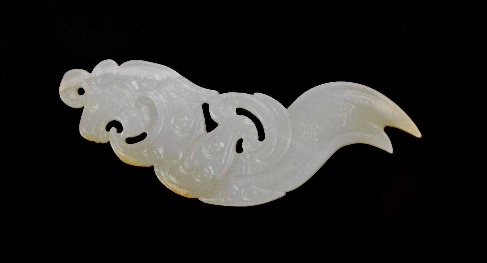 White Jade Pendant: An archaistic white jade 'Qilong' pendant Qing dynasty The stone of a pale celadon colour, with touches of russet and paler white. L: 3 in,; 7.8 cm.