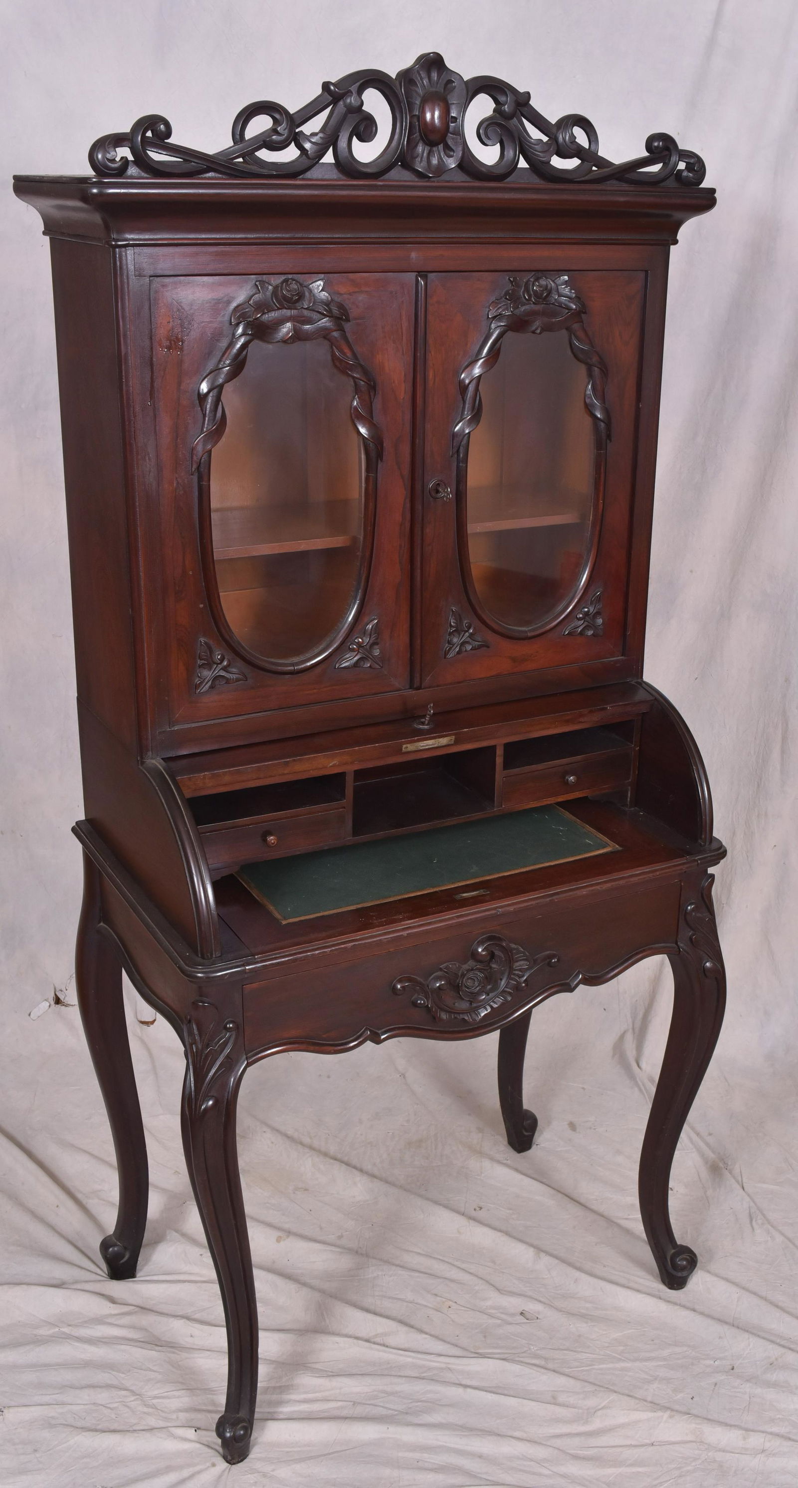 Rosewood Victorian cylinder roll desk: Rosewood Victorian cylinder roll desk, top with pierced carved crest, over 2 doors with oval glazed panels, pull out writing surface with 2 drawer interior, raised on cabriole legs, centering lower dr