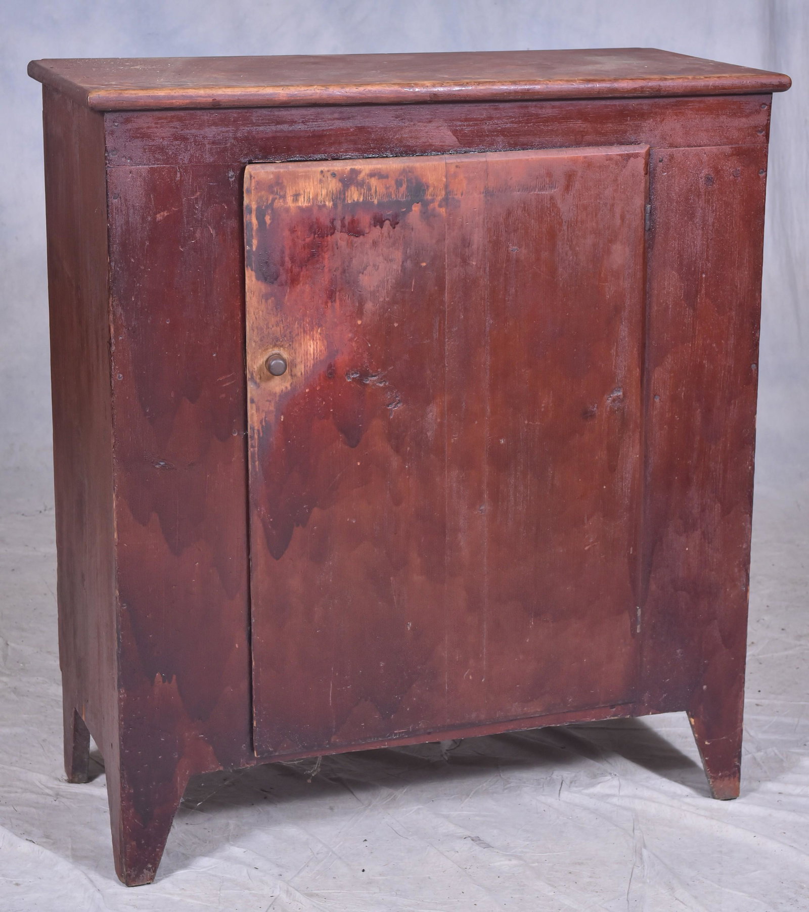 Pine one-door wall cupboard: Pine one-door wall cupboard, single plank & batten door concealing interior with geometric wallpaper shelves, old reddish-brown painted surface, 39-3/4" w x 46" h x 18" d