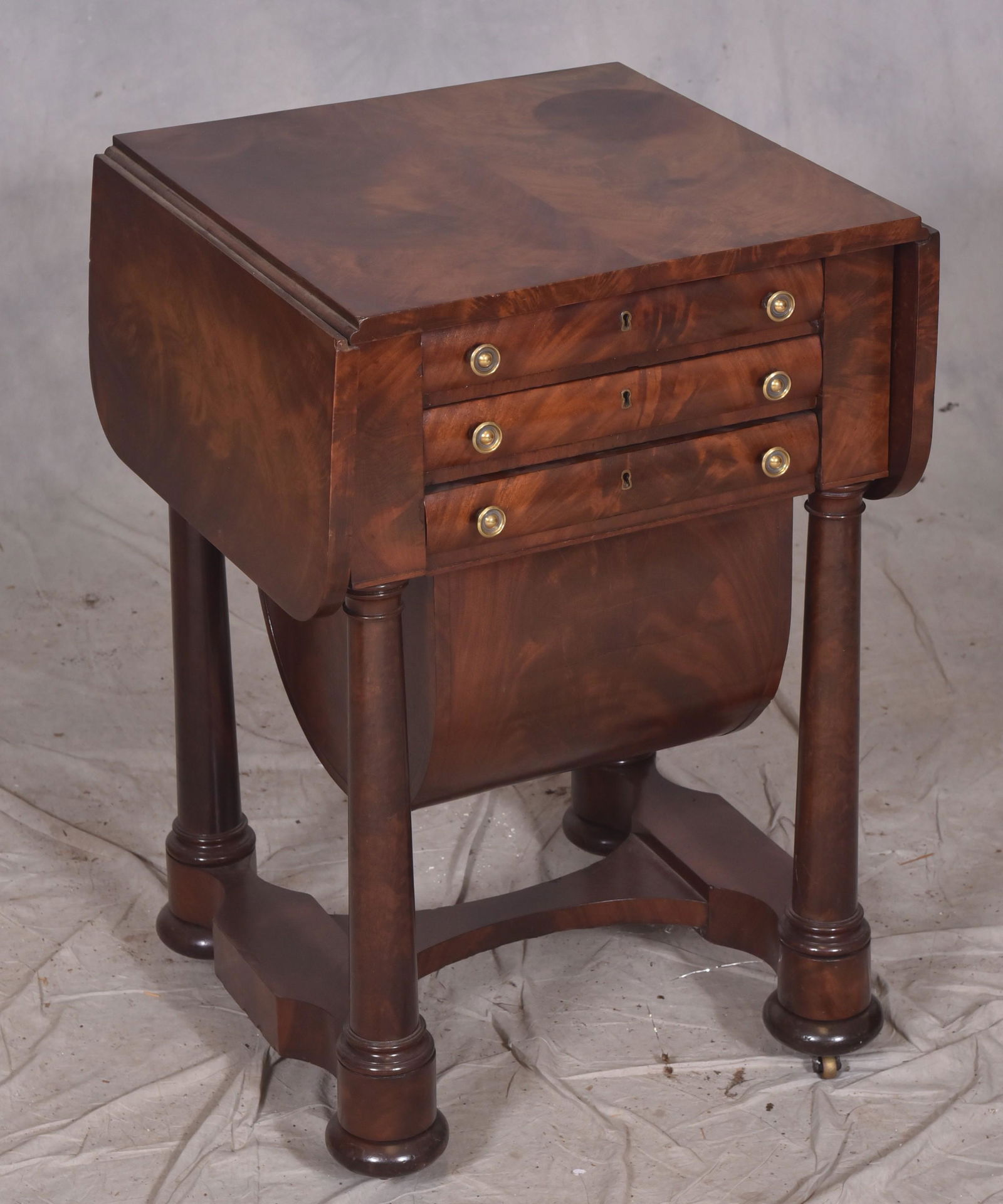 Mahogany Federal 3-drawer sewing stand: Mahogany Federal 3-drawer sewing stand, drop leaves, bottom drawer with work basket, top drawer with fitted interior, on turned column form legs to scalloped stretcher base, 18" w x 19" d x 29-1/2" h