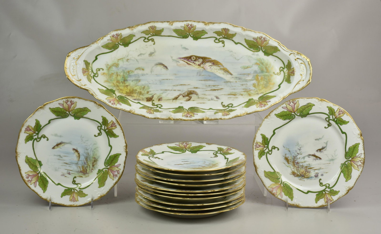 (13) Pc Haviland Limoges Fish Set: Theodore Haviland Limoges porcelain fish set, c/o fish platter, 23" x 9-3/4" , (12) 9-7/8" plates, hand painted fish motif with gilt scrollwork and floral border, artist signed L Martin: . Provenance: