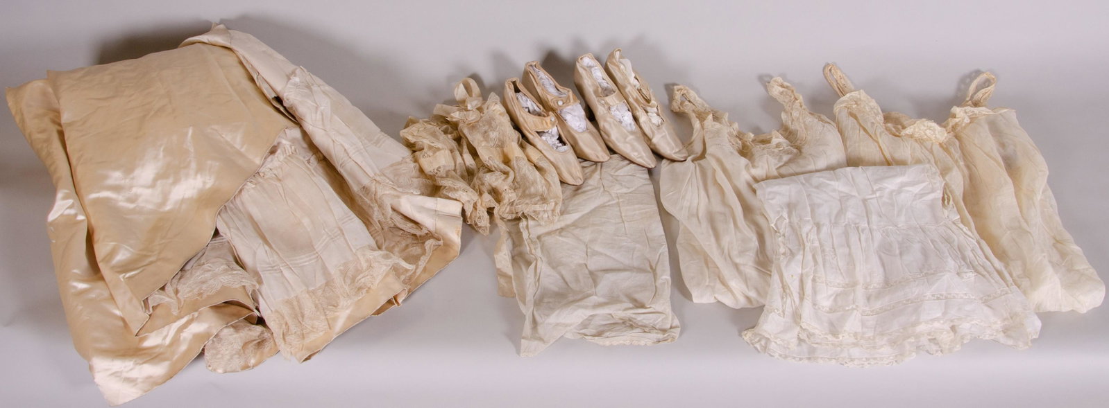 Victorian Undergarment and Wedding Grouping: Victorian undergarment and wedding grouping c/o (2) pairs silk wedding heels with glass opalescent buttons, silk bridal skirt with elongated train and ruffled lace attached slip, sheer banded floral l